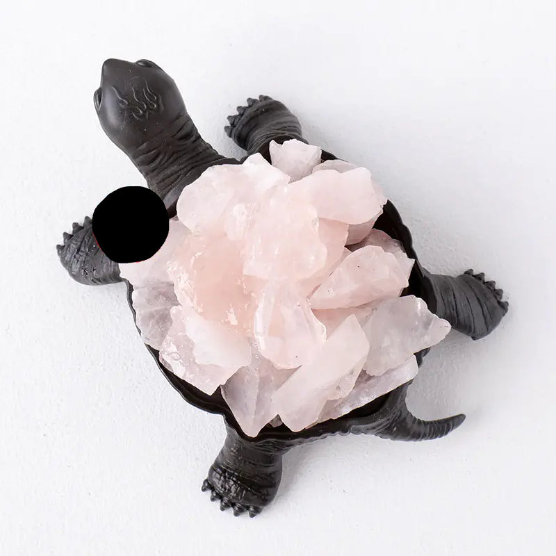 Decorative turtle figure with pink crystal-like stones on a white background