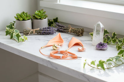 Pair of orange elf ear-shaped headphones on a green background