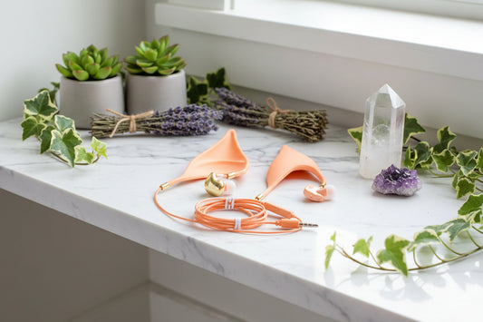 Pair of orange elf ear-shaped headphones on a green background