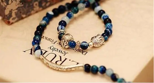 Blue beaded bracelet with charms on a textured surface