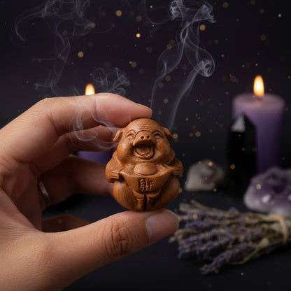Hand holding a small wooden pig figurine with a blurred background