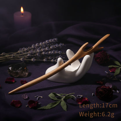 Wooden hair stick on a white stand with product details on a light background
