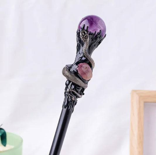 Decorative crystal magic wand with amethyst gem and black metal design on a light background
