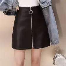 Person wearing a black leather mini skirt with a denim jacket and holding a handbag.