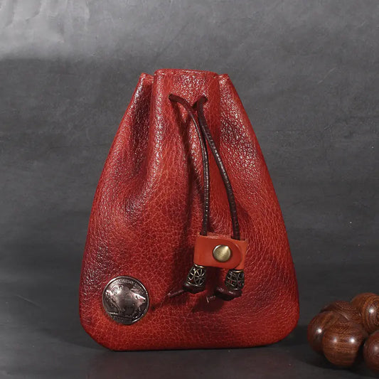 Red leather drawstring pouch with decorative elements on a dark background