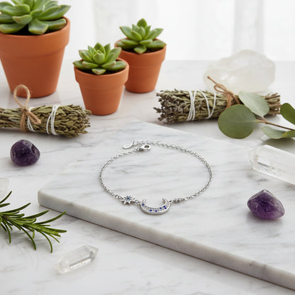 Silver bracelet with star and moon designs on a white background