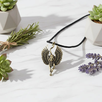 Bronze winged cat pendant on a stone surface