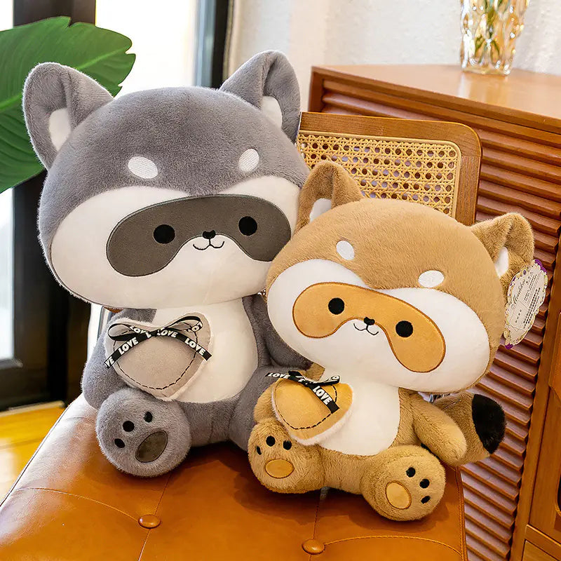 Two plush toys, one gray and one brown, sitting on a chair with a blurred background.