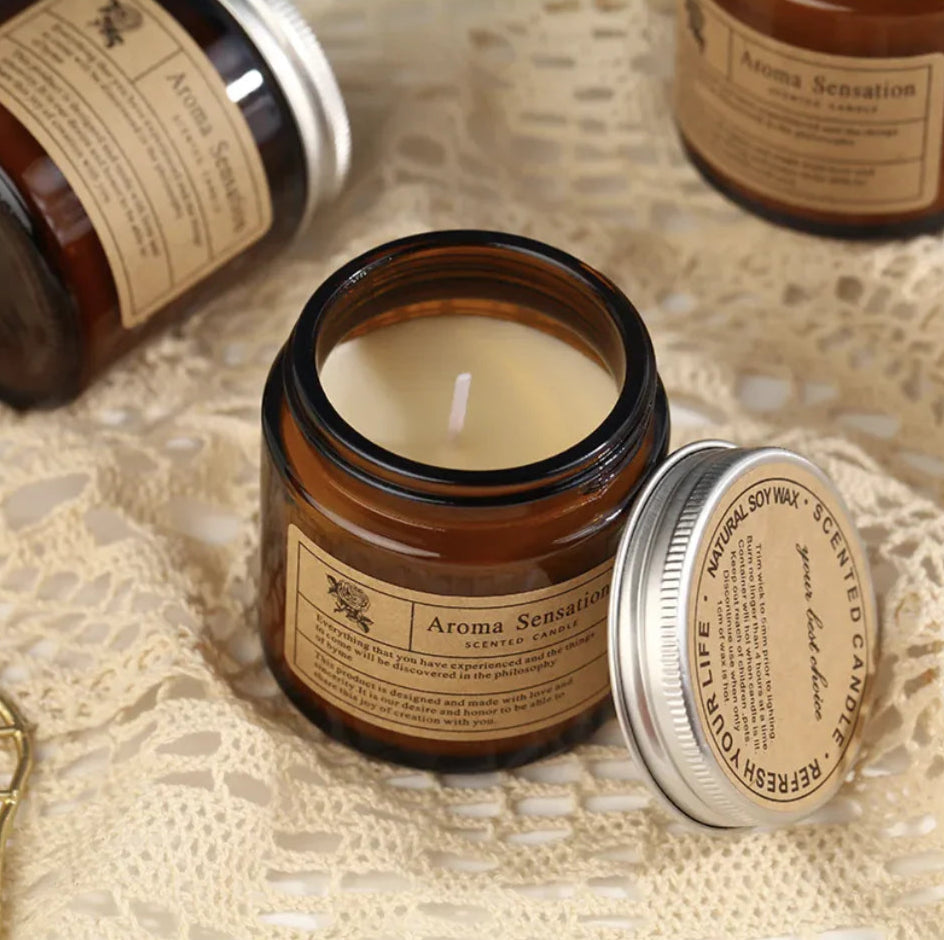 Aroma Sensation scented candle in a glass jar with a metal lid on a textured surface.