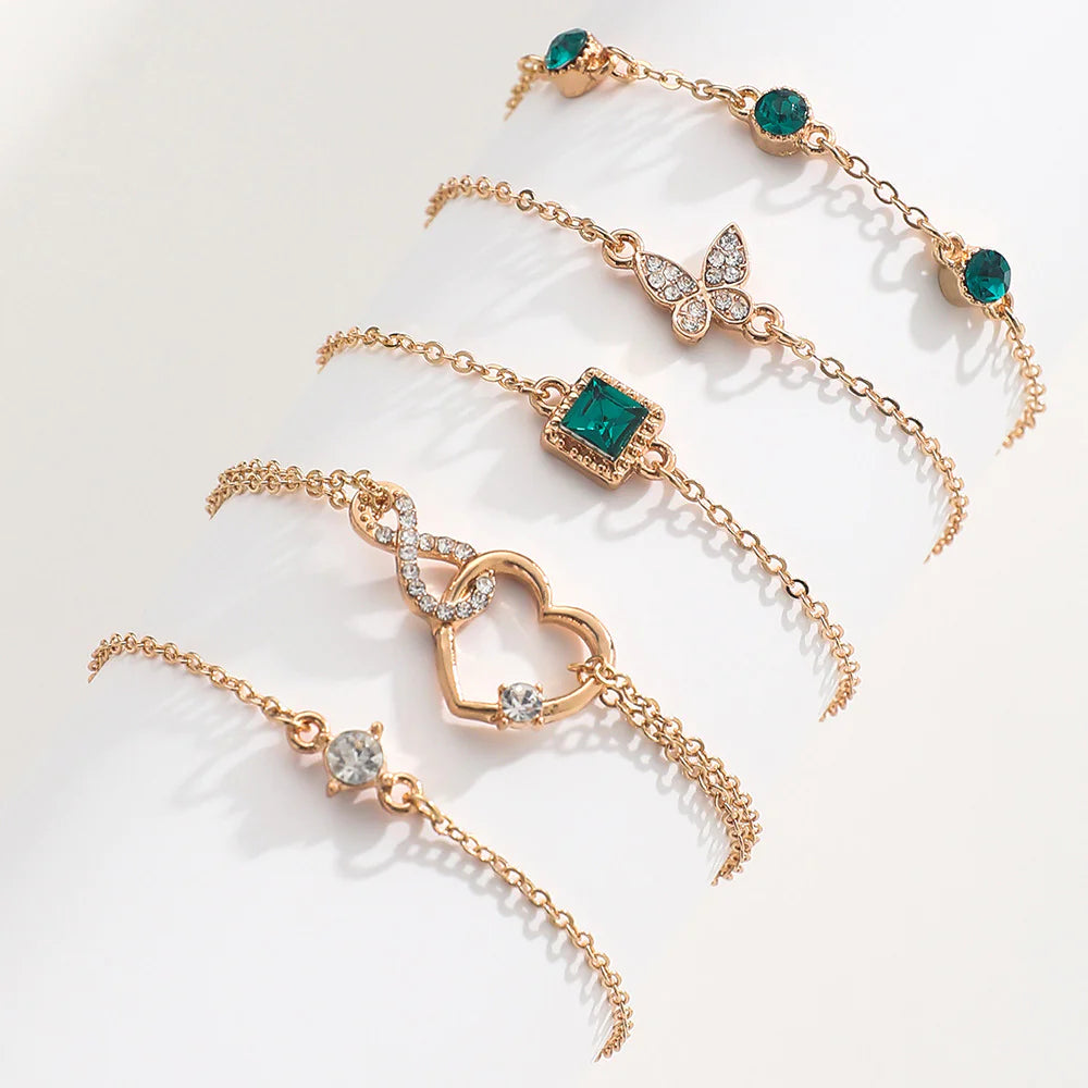 Gold bracelets with emerald green gemstones on a light background