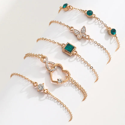 Gold bracelets with emerald green gemstones on a light background