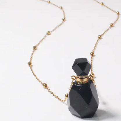 Black perfume bottle with gold chain on a white background