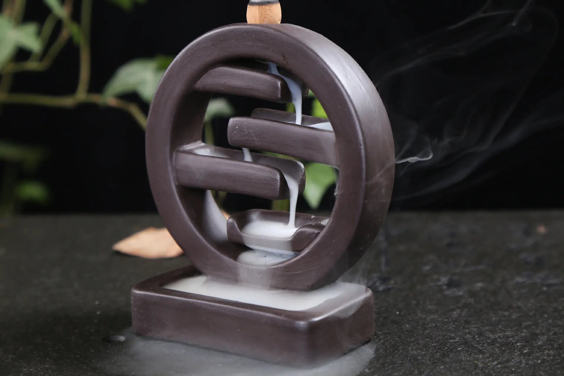 Incense burner with smoke on a dark surface