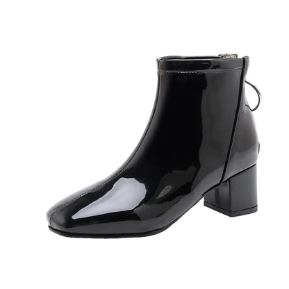 Black patent leather ankle boot on a white background