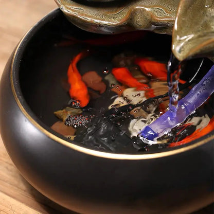 Decorative fountain with goldfish in a bowl on a wooden surface