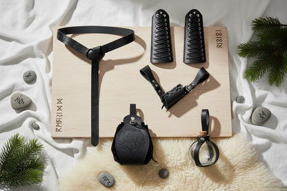 Collection of black leather and glass items including a belt, cuffs, and pouches on a white background.