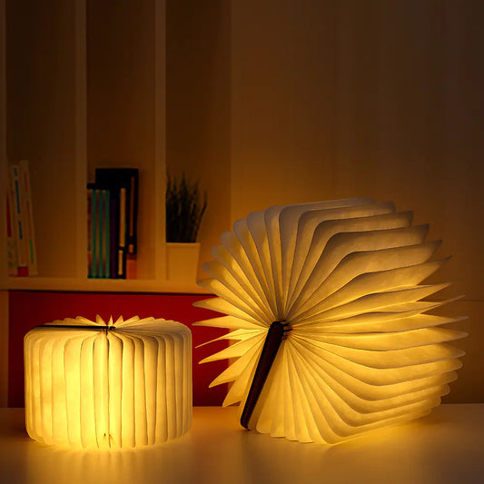 Two glowing book-shaped lamps on a surface with a blurred indoor background