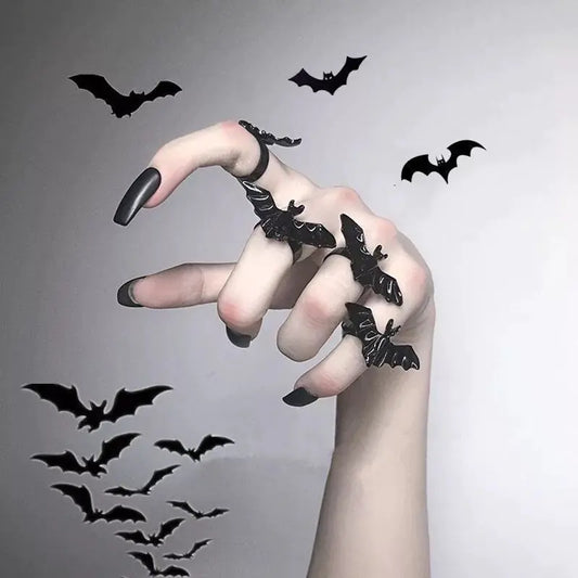 Hand with black nail polish and decorative bats on fingers against a gray background