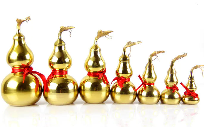 Set of gold gourd-shaped ornaments with red ribbons on a white background