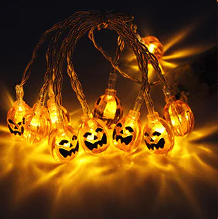 String lights shaped like pumpkins with glowing faces on a dark background