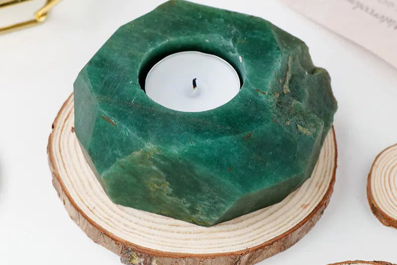 Green stone candle holder with a white candle on a wooden base