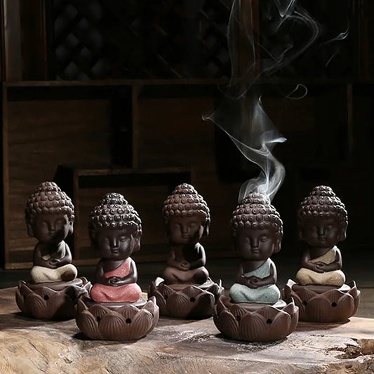 Five small Buddha figurines with incense burning on a wooden surface.