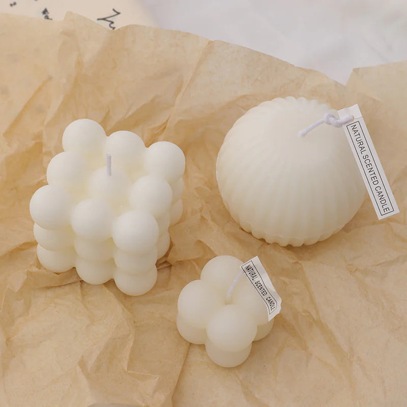 Three white bubble-shaped candles on brown paper with 'Naturally Scented Candle' labels.
