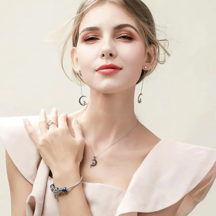 Woman wearing jewelry including a necklace, ring, and bracelet against a light background
