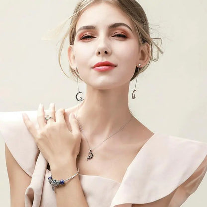 Woman wearing jewelry including a necklace, ring, and bracelet against a light background