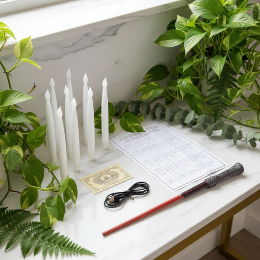 White candles, a small gold item, a black cord, and a red object on a dark surface with a 'Beginner's Guide to Wands' sheet.