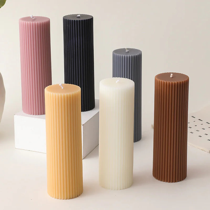 Set of six ribbed candles in different colors on a light surface.