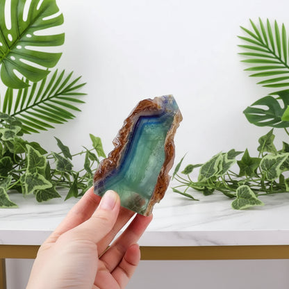 Hand holding a colorful crystal with measurement text on a white background