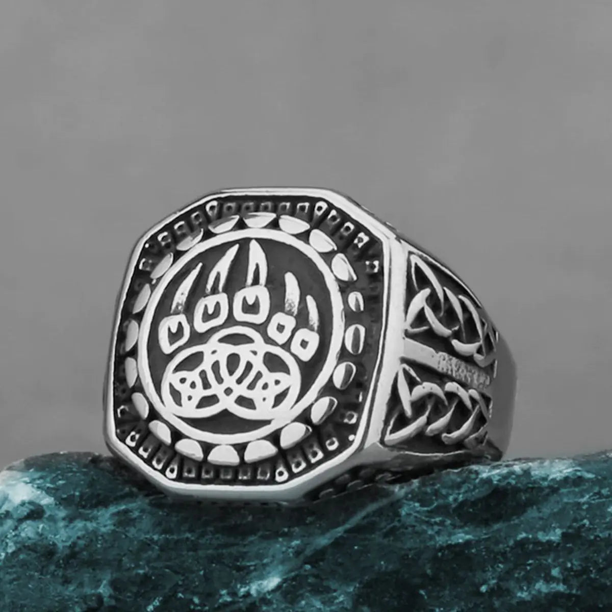 Silver ring with paw design on a gray background