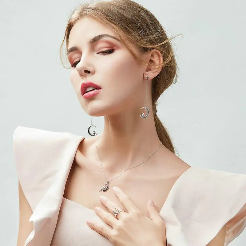 Woman wearing silver jewelry including earrings, necklace, and ring on a light background