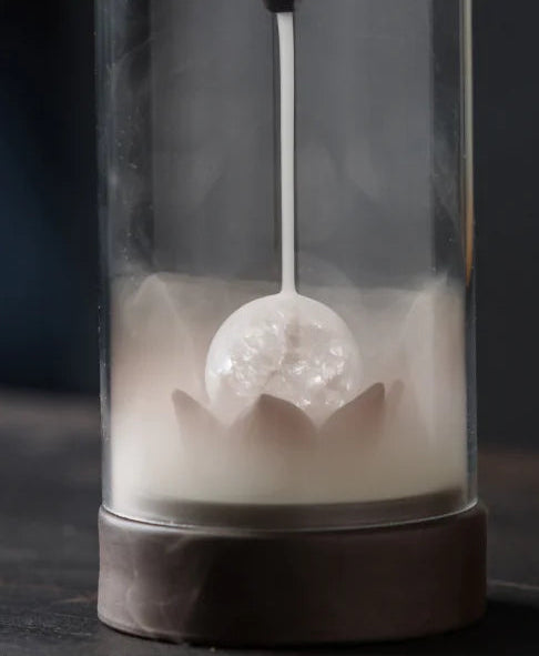 Tea bag with a decorative design in a clear container on a dark background