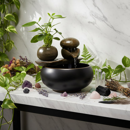 Decorative water fountain with rocks and a plant on a wooden surface