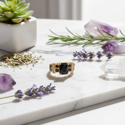 Gold ring with black gemstone and crown-like design on a dark background