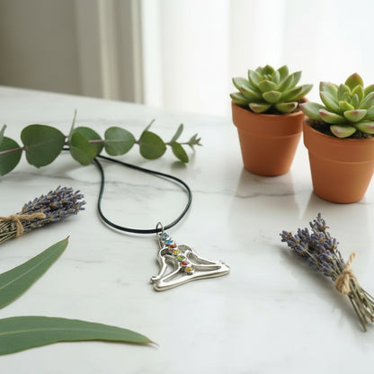 Silver pendant of a meditating figure with colorful gemstones held in hand