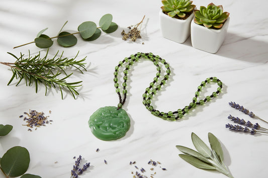 Green jade pendant on a beaded necklace against a white background