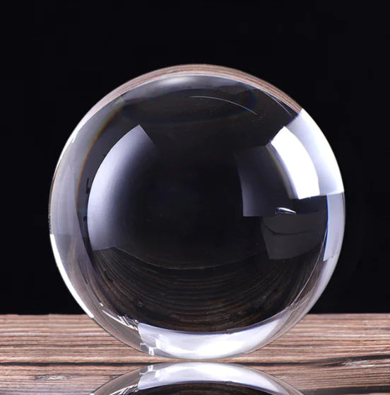Clear crystal ball on a wooden surface with a black background