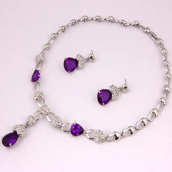 Jewelry set with purple heart-shaped stones on a light pink background