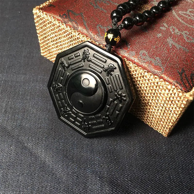 Black pendant with intricate designs on a textured surface
