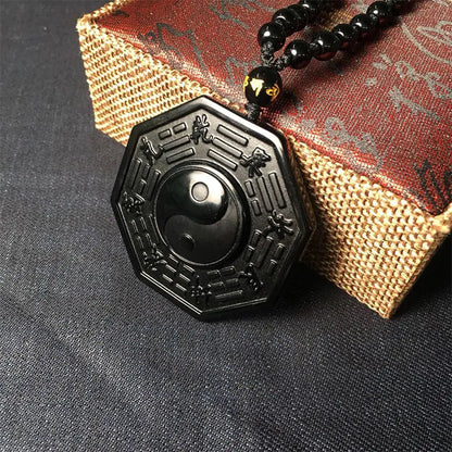 Black pendant with intricate designs on a textured surface