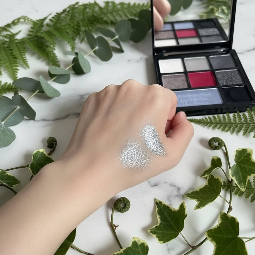 Hand with silver glitter makeup swatch in front of a makeup palette
