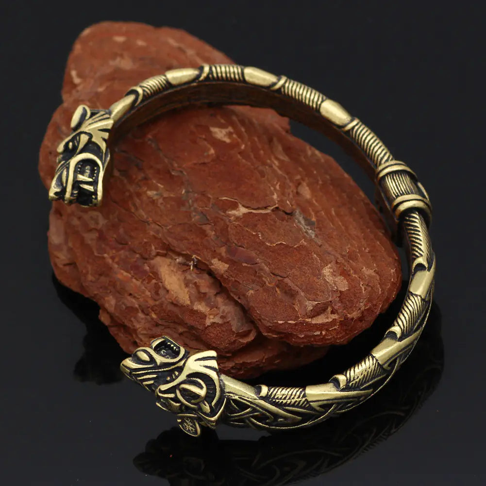 Bronze bracelet with intricate designs on a dark background