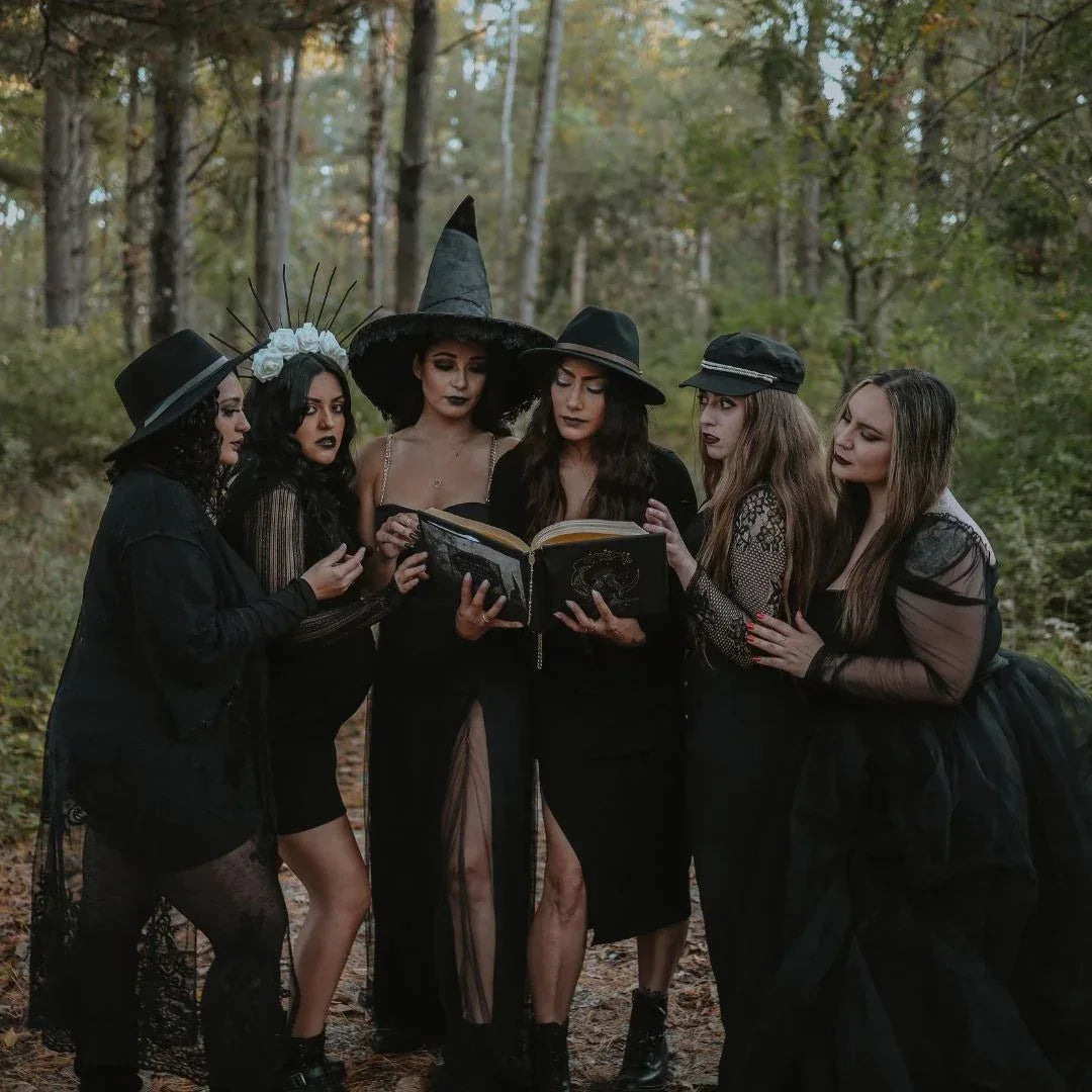 coven of witches in forest holding grimoire