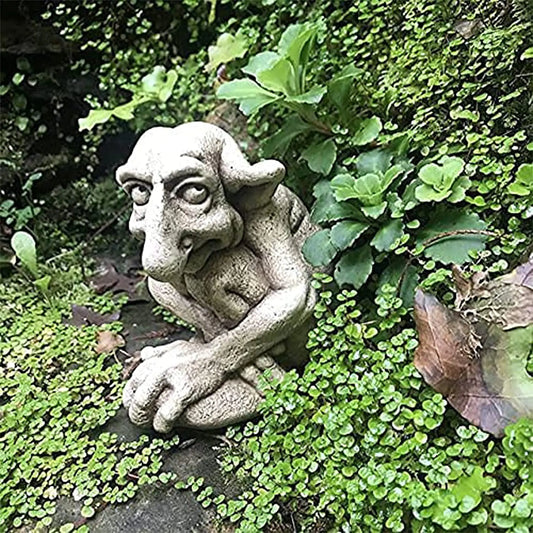 Gargoyle statue amidst green foliage