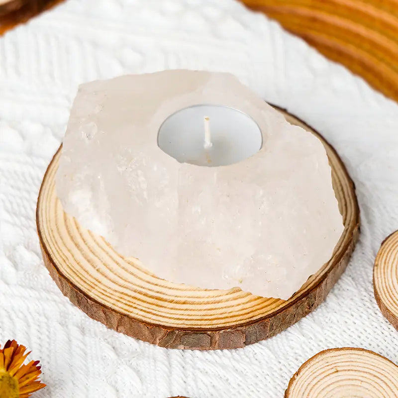 Candle in a coconut shell on a wooden coaster with a white cloth background