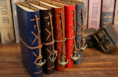 Set of leather-bound books with decorative straps on a wooden surface