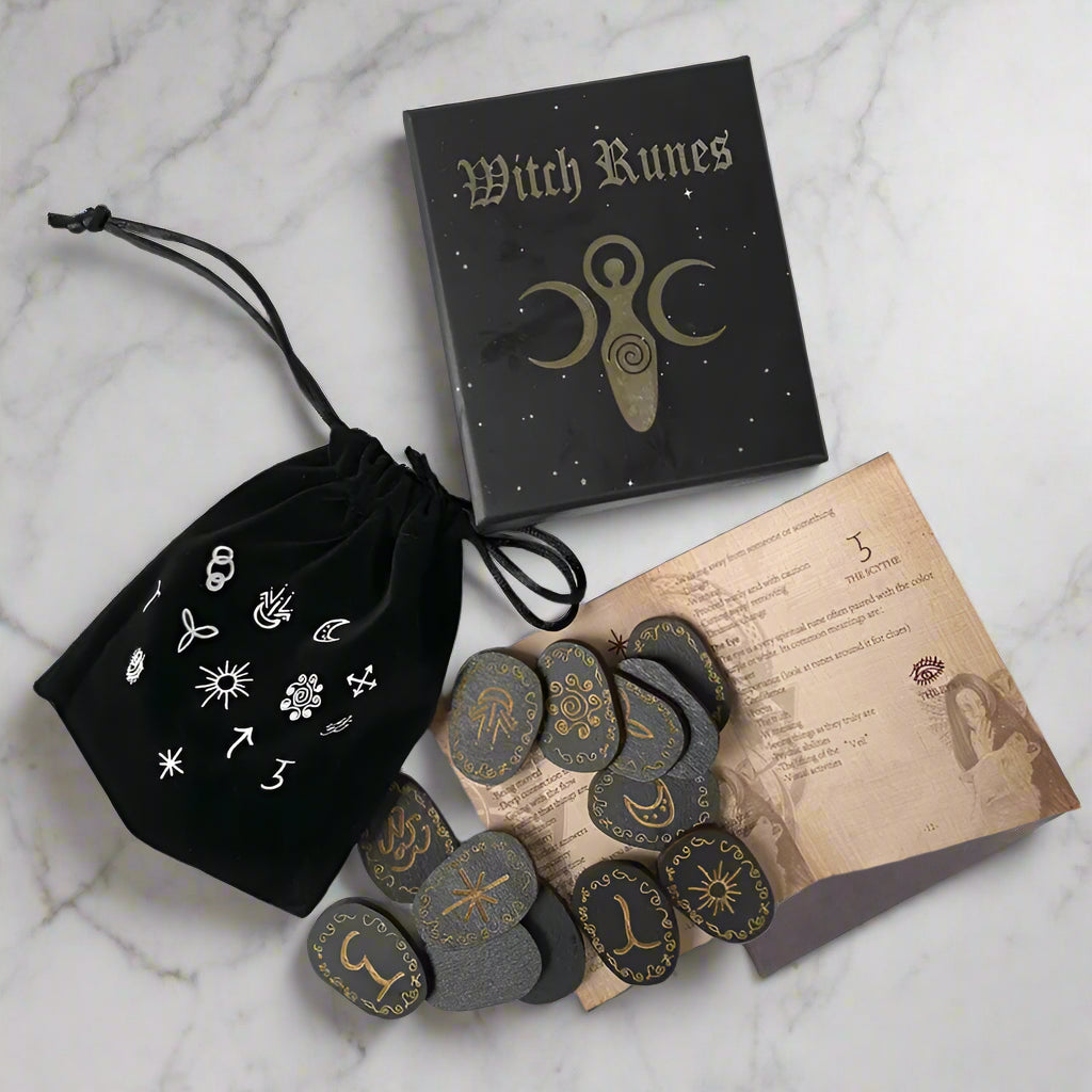 Witch Runes set with black drawstring bag, book, and stones on a gray surface